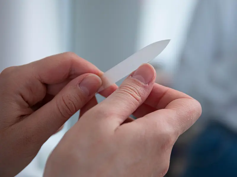 Hand filing nails for smooth and even shaping.